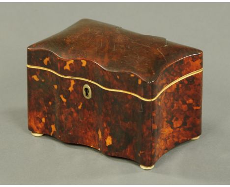 An early 19th century tortoiseshell tea caddy, small form, serpentine fronted and with two interior lidded compartments.  Len