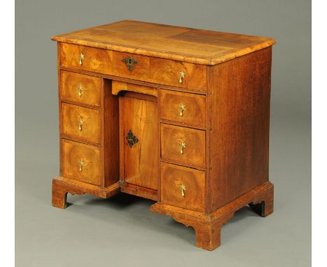 An early 18th century oyster veneered walnut kneehole desk, the top with crossbanded moulded edge above a series of drawers a