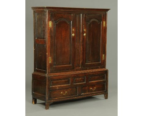A Georgian oak cupboard, with moulded cornice above a pair of arched panelled doors opening to hanging space, the base fitted