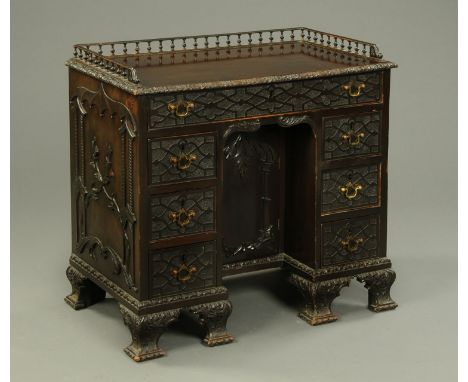 A 19th century blind fretwork carved kneehole desk, with three quarter spindled gallery, carved moulded edge, series of drawe