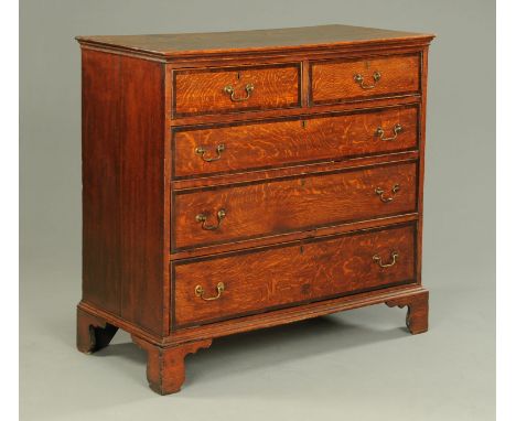 A North Country oak and mahogany crossbanded chest of drawers, two short and three long with brass drop handles and cockbeadi