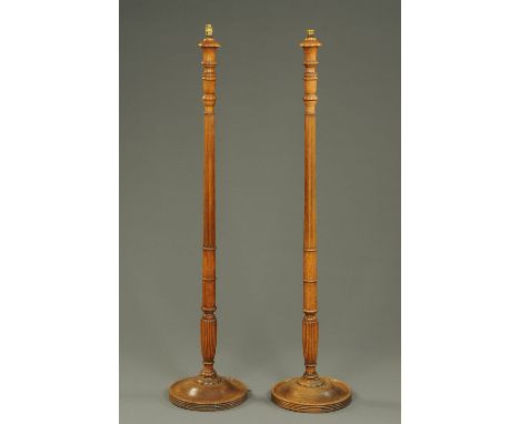 A pair of oak standard lamps, with turned and reeded columns and raised on circular bases.  Height excluding light fitting 15