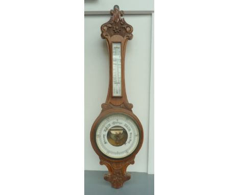 A wall hanging wooden barometer with carved reliefs