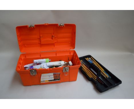 A large selection of oil paints and brushes in an orange toolbox