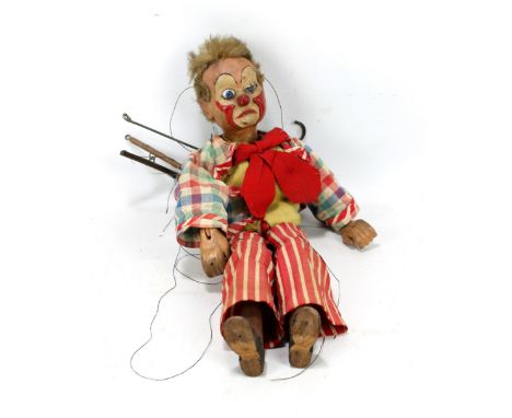 An early to mid-20th century wooden marionette modelled as a clown with painted features, glass eyes and multicoloured clothe