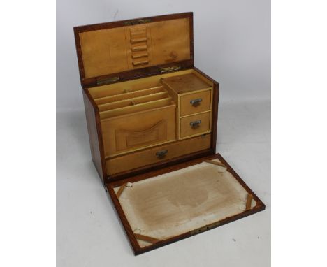 An Edwardian oak travelling stationery cabinet with hinged lid and fall front set with various compartments, two short and on