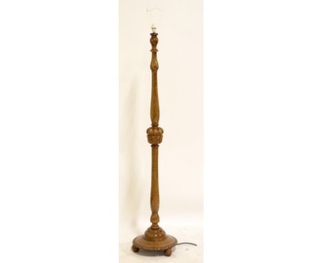 A 1940s oak standard lamp with cup and cusp central decoration and circular base.