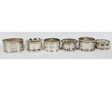 Six variously hallmarked silver napkin rings including a George V engine turned example with vacant circular cartouche, G Lov