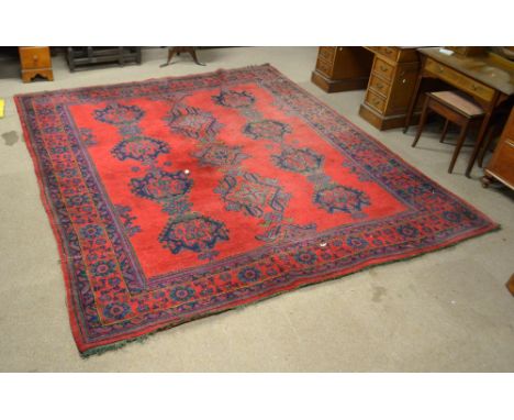 A Turkish design carpet with central red ground panel set with three rows of medallions within a floral decorated border, bea