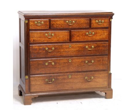A large early 19th century oak chest of five short and three long graduated drawers raised on bracket feet with rounded corne