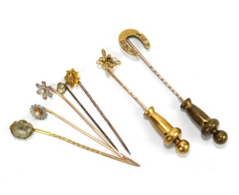 Six yellow metal stick pins to include a shoe horn shaped example and a bee shaped example, and a 15ct gold topped example (7