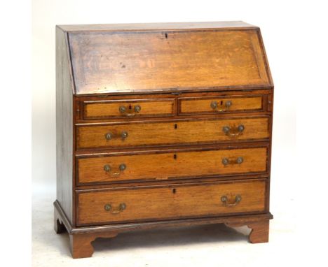 A late George III oak and mahogany crossbanded bureau with fall-front above two short and three long graduated drawers raised