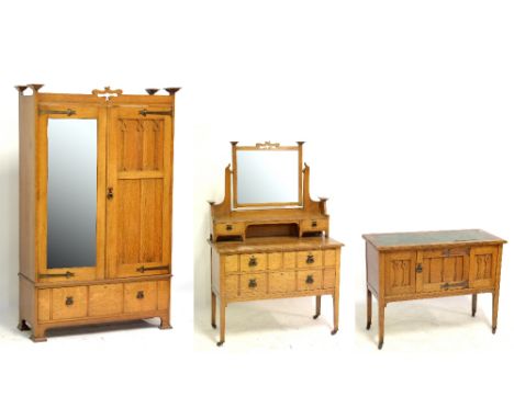 An Edwardian Arts and Crafts oak three piece bedroom suite comprising mirrored and panelled door wardrobe with drawer to base