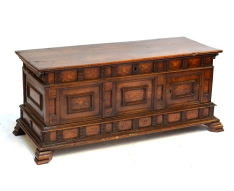 An early 18th century Italian walnut and inlaid cassone with hinged lid above decorated front panels and raised on stepped br
