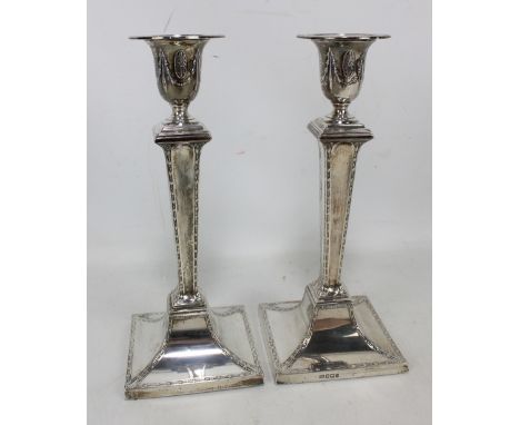 HARRISON BROS &amp; HOWSON; a pair of Edward VII hallmarked silver Neo-classical style candlesticks, the urn shaped capitols 