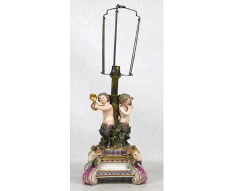 A late 19th/early 20th century Continental porcelain lamp base modelled as three fauns on circular base above square pedestal
