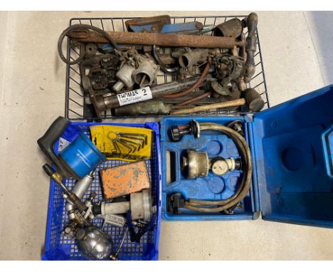 A crate of parts and equipment, a radiator leak checker tool and a tray of tools including a spray gun. 
