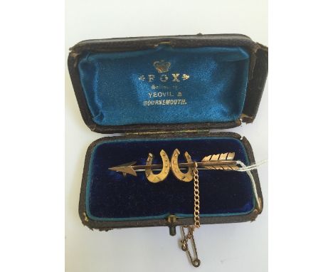 A 15 carat gold bar brooch modelled as an Arrow through two Horseshoes.