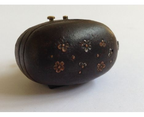A Japanese Snaphance walnut shaped flintlock tinder lighter Netsuke with inlaid flower head decoration to lid in iron case, p