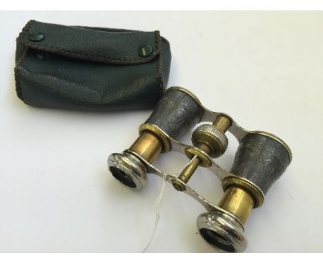 A pair of early 20th century opera glasses with white metal mounts decorated with stags and hunting dogs in original green le