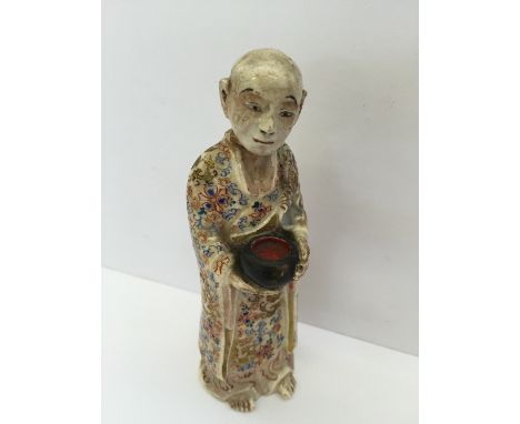 An unusual late 19th century Satsuma figure modelled as a monk wearing highly decorated cloak and holding a bowl (head re-glu