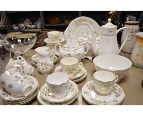 An antique partial tea service having white ground with gilt floral design, tea and coffee pots, cups and saucers and more to