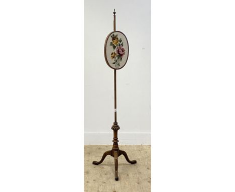 An Edwardian mahogany pole screen, the oval banner with embroidered panel worked in a floral design rising on a turned column