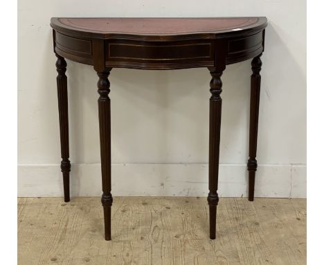 A Georgian style demi-lune mahogany console table, the tooled red leather top above a drawer and raised on fluted and turned 