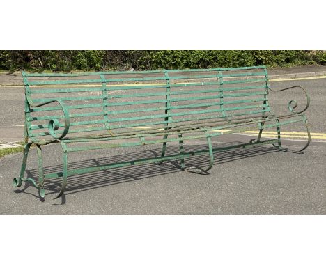 A large riveted strapwork iron garden bench, first half of the 19th century, with scrolling arms and supports. H90cm, W276cm,