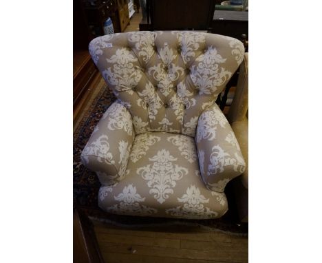 An Edwardian armchair, the deep button backed upholstery with floral decoration, raised on mahogany ring turned supports.