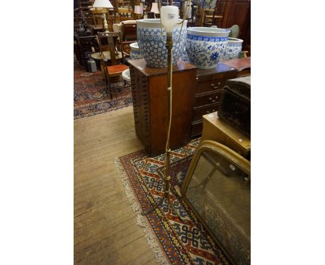 An early 20th Century brass standard lamp, raised on three legs with paw feet (sold electrically untested).