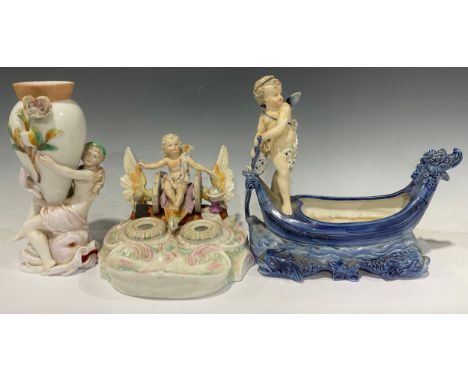 A 19th century German porcelain inkstand, surmounted with a winged putti in winged chariot, above two removable inkwells and 