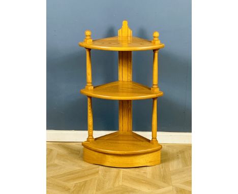 A blonde Ercol bow fronted three tier corner whatnot, Ercol badge to the bottom shelf, 47cms wide x 32cms deep x 80cms high. 