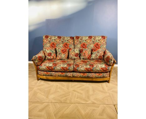 An Ercol renaissance wooden framed three seater sofa with floral upholstery and cushions, Ercol badge to the frame, 199cms wi