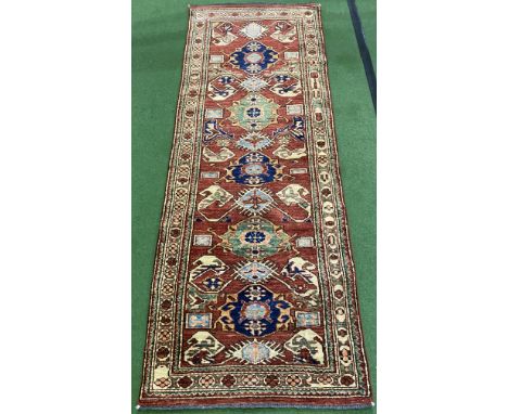 Red ground handmade Chechen runner, 210cm length x 80cm width. Estimate £95-150