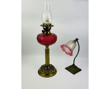 An attractive oil lamp with a decorative circular brass base and reeded central column, a ruby red moulded glass reservoir an