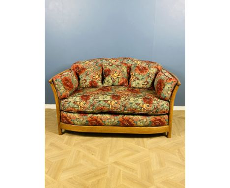 An Ercol Renaissance wooden framed two seater studio sofa with floral upholstery and cushion, Ercol badge to the frame, 145cm