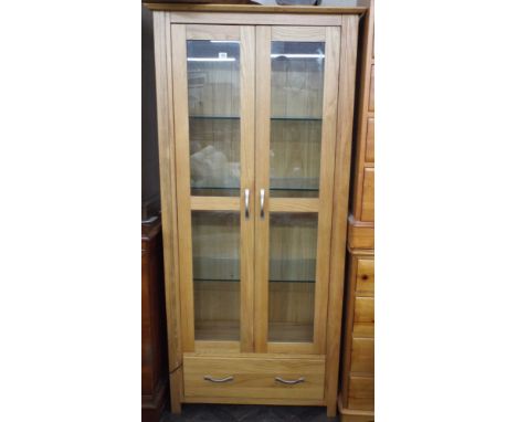 A light oak two door glazed bookcase with adjustable glass shelves, 2'9" wide 
