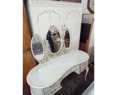 A cream and gilt decorated two door wardrobe and a matching kidney shaped dressing table with triple mirrors 