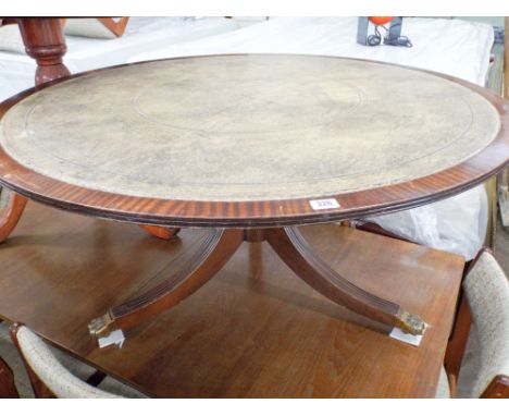 A circular reproduction mahogany coffee table with inset leather top on a tripod base 