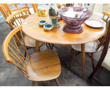 A oval light Ercol dining table together with four matching crossover stick back chairs 38 inches by 34 inches 