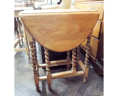 An oval light oak gate legged table on barley twist legs, 2' wide 