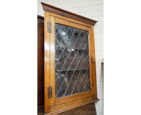 An oak wall hanging corner cabinet with glazed lead light door 