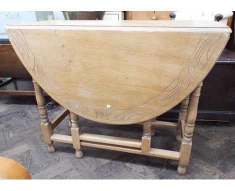 An oval light oak gate legged table on turned legs, 3' wide 