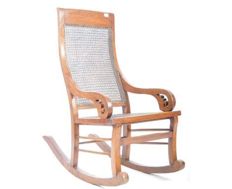 An early 20th Century Chinese Qing Dynasty antique hardwood rocking chair having a woven cane backrest and seat. Shaped scrol