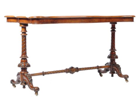 A 19th Century Victorian English antique walnut stretcher table writing table desk having a double serpentine top raised on a