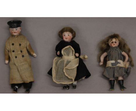 Three late 19th/early 20th century miniature porcelain dolls: largest is a male doll chauffeur with bisque shoulder head with