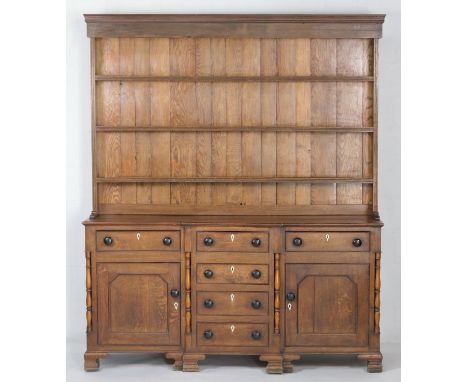 Montgomery oak enclosed dresser, circa 1820-40, with later plate rack, having three shelves over a breakfront base with four 