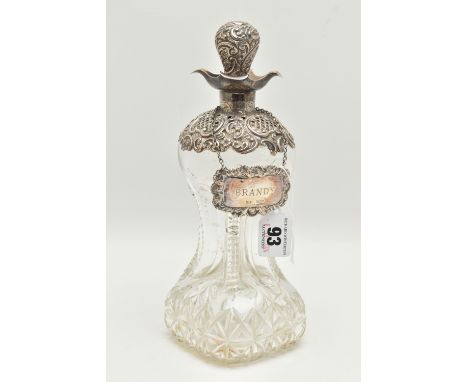 A LATE VICTORIAN GLASS AND SILVER DECANTER, the hour glass bottle with silver collar and stopper embossed with flowers and sc