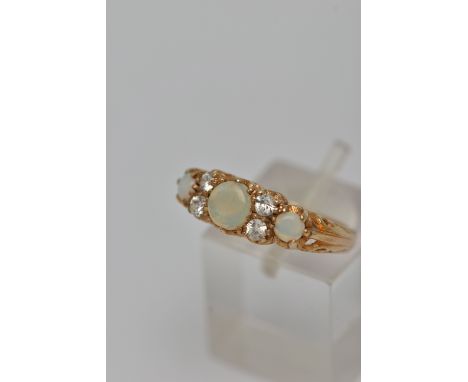 A 9CT GOLD GEM SET RING, three round opals, prong set in yellow gold, accented with one circular cut paste stone, the additio